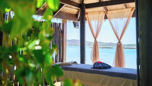 A wooden structure with a bed and a view of the sea.