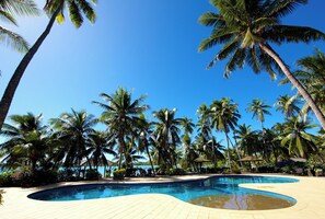 Una piscina rodeada de palmeras y un cielo azul despejado.