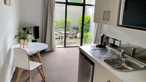 A modern kitchen with a built-in dishwasher, a stainless steel sink, and a flat-screen TV mounted above the counter. - Alpine Lake Motor Lodge (Taupo)