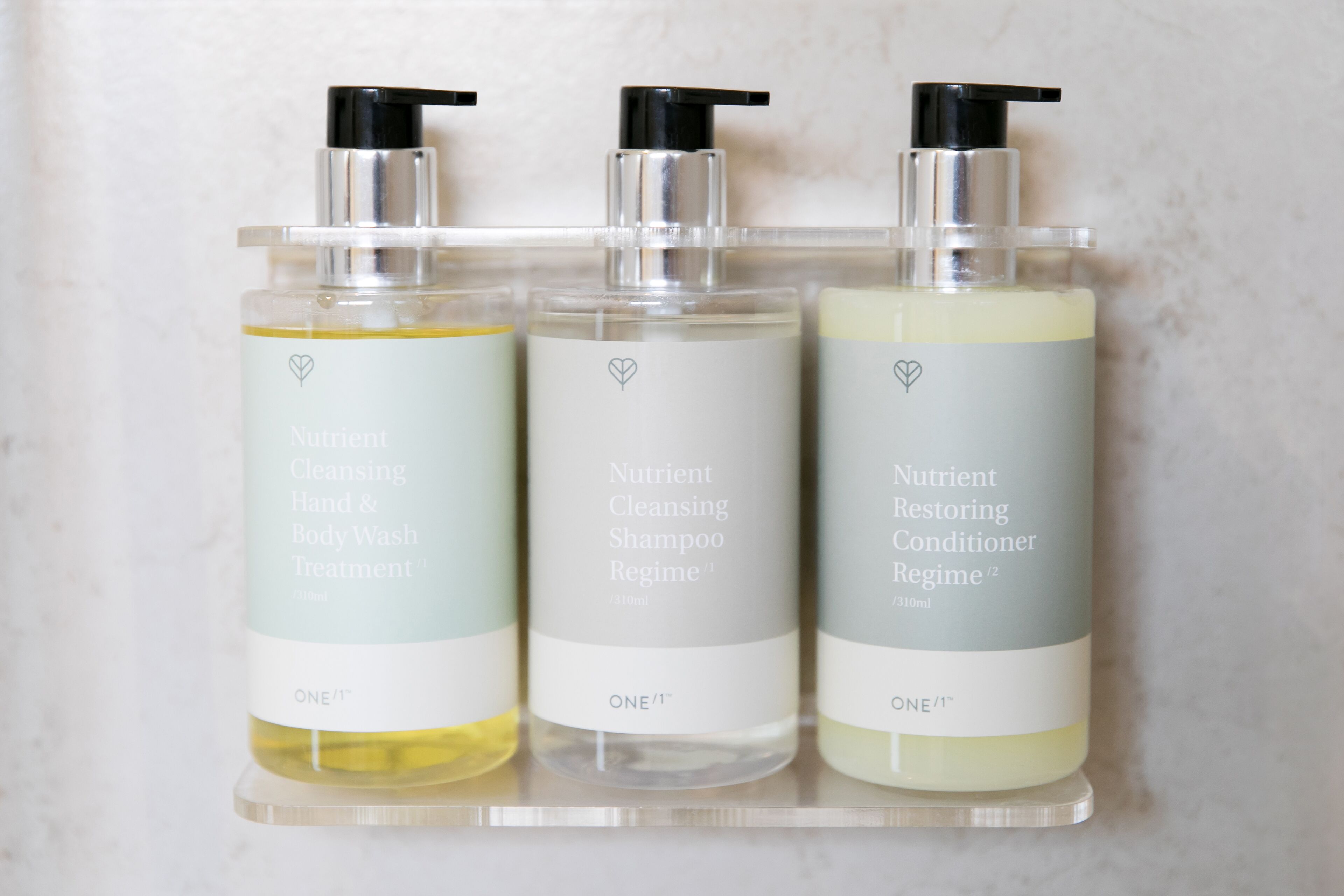 Tres botellas de producto Nutrient sobre una estantería transparente.