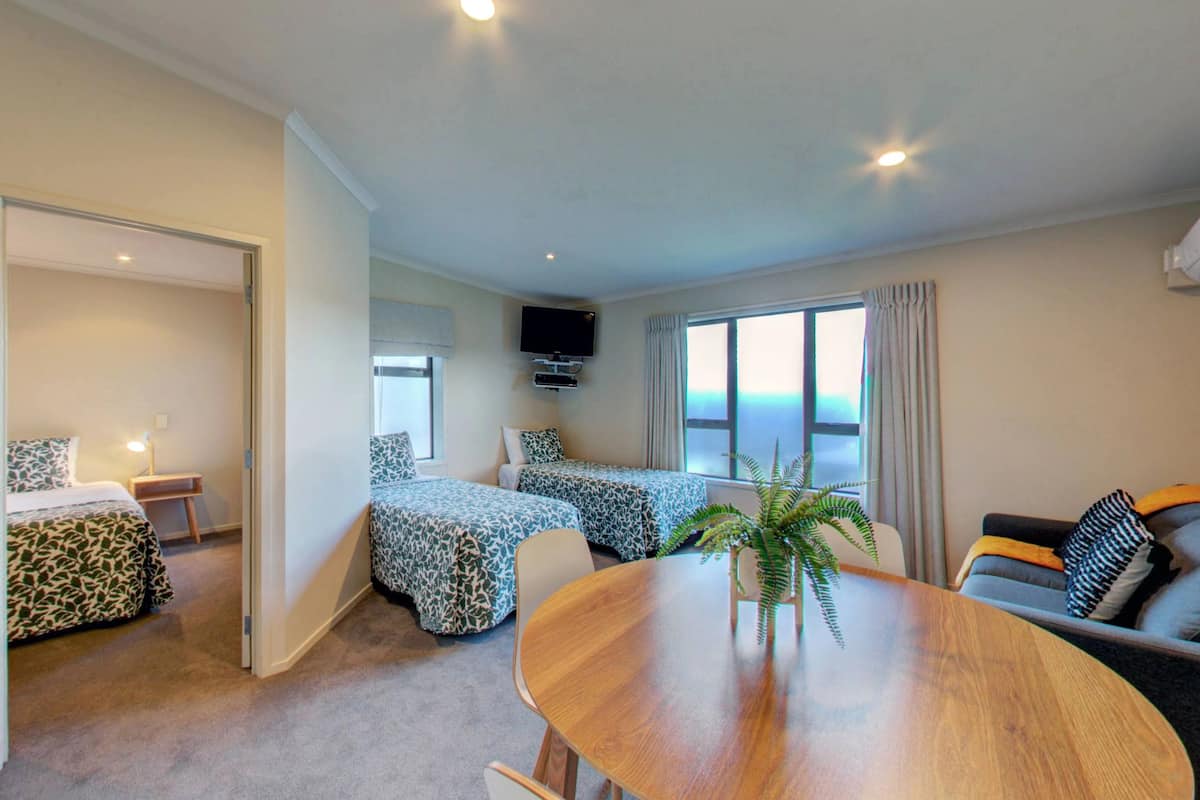 Una habitación de hotel con cama, sofá, mesa de comedor y televisor.