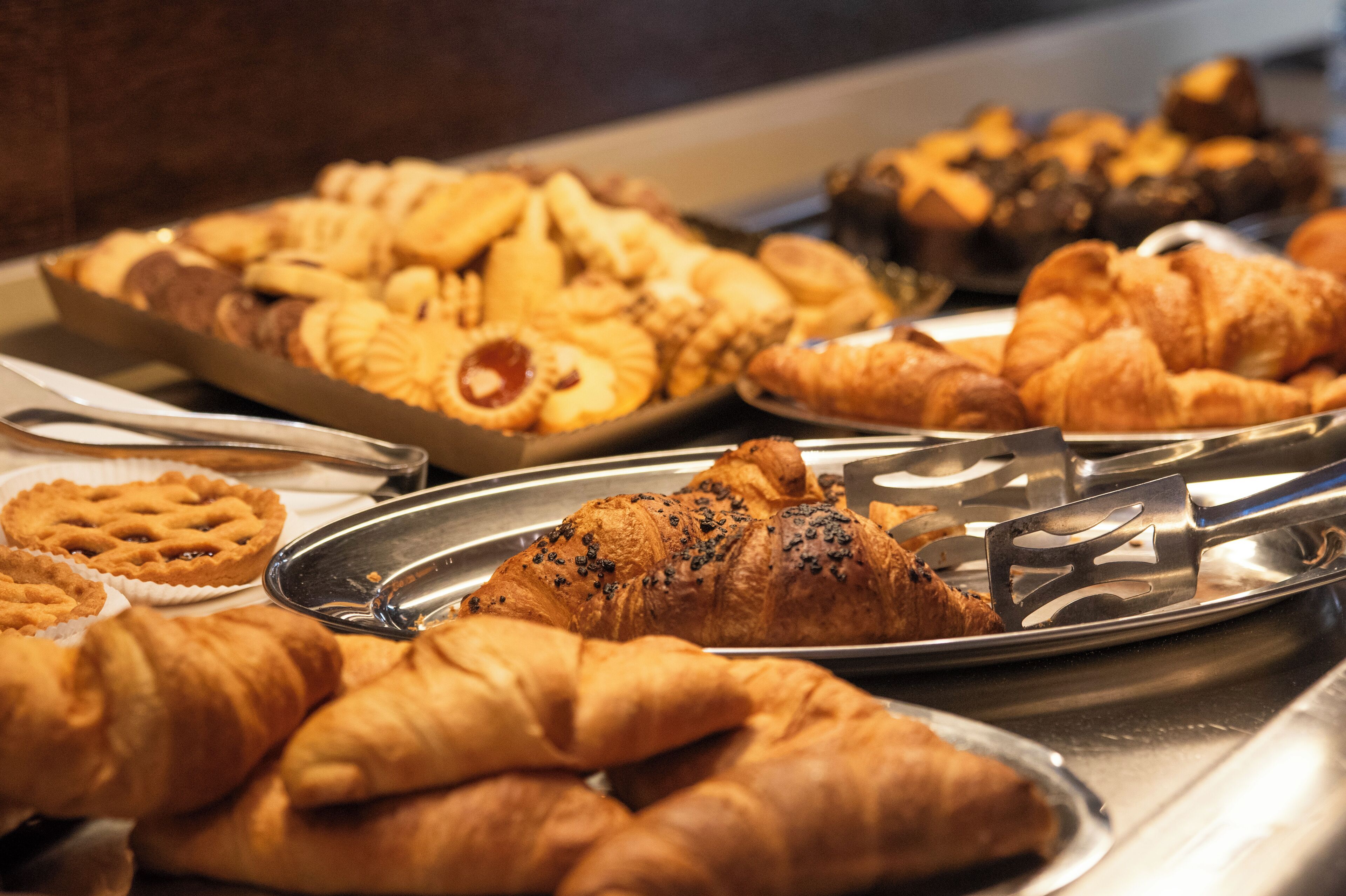 A variety of baked goods including pies, tarts, and croissants on trays.