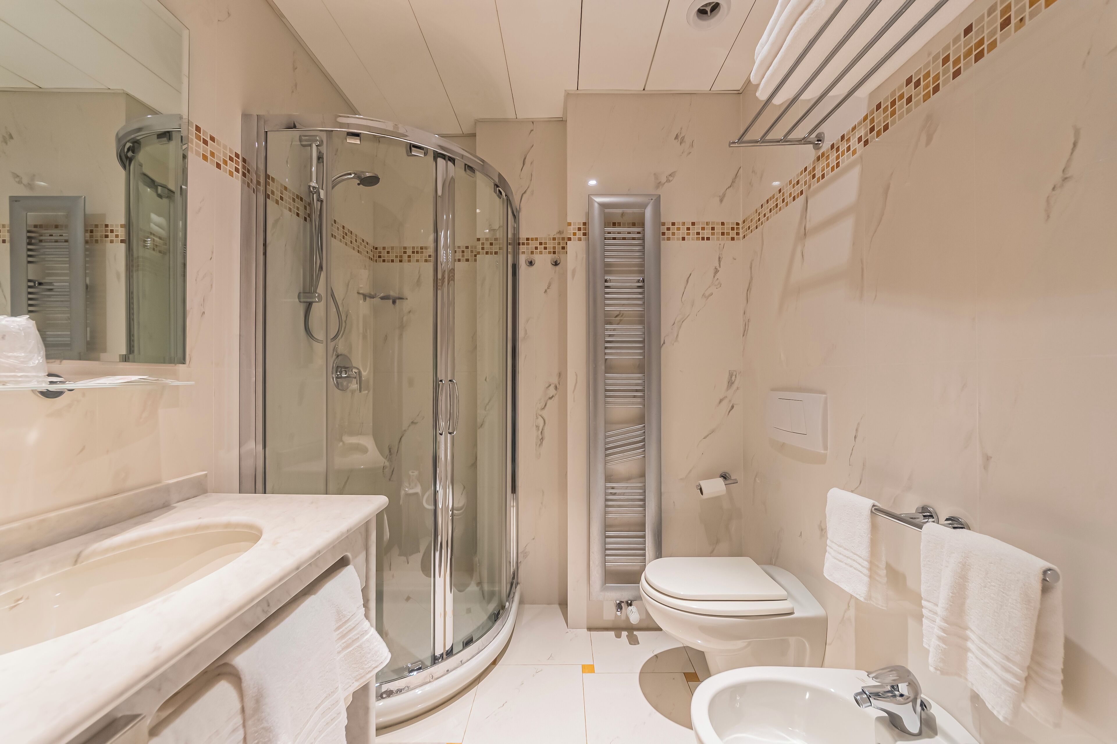 A modern bathroom with a glass-enclosed shower, a built-in toilet, and a sink.