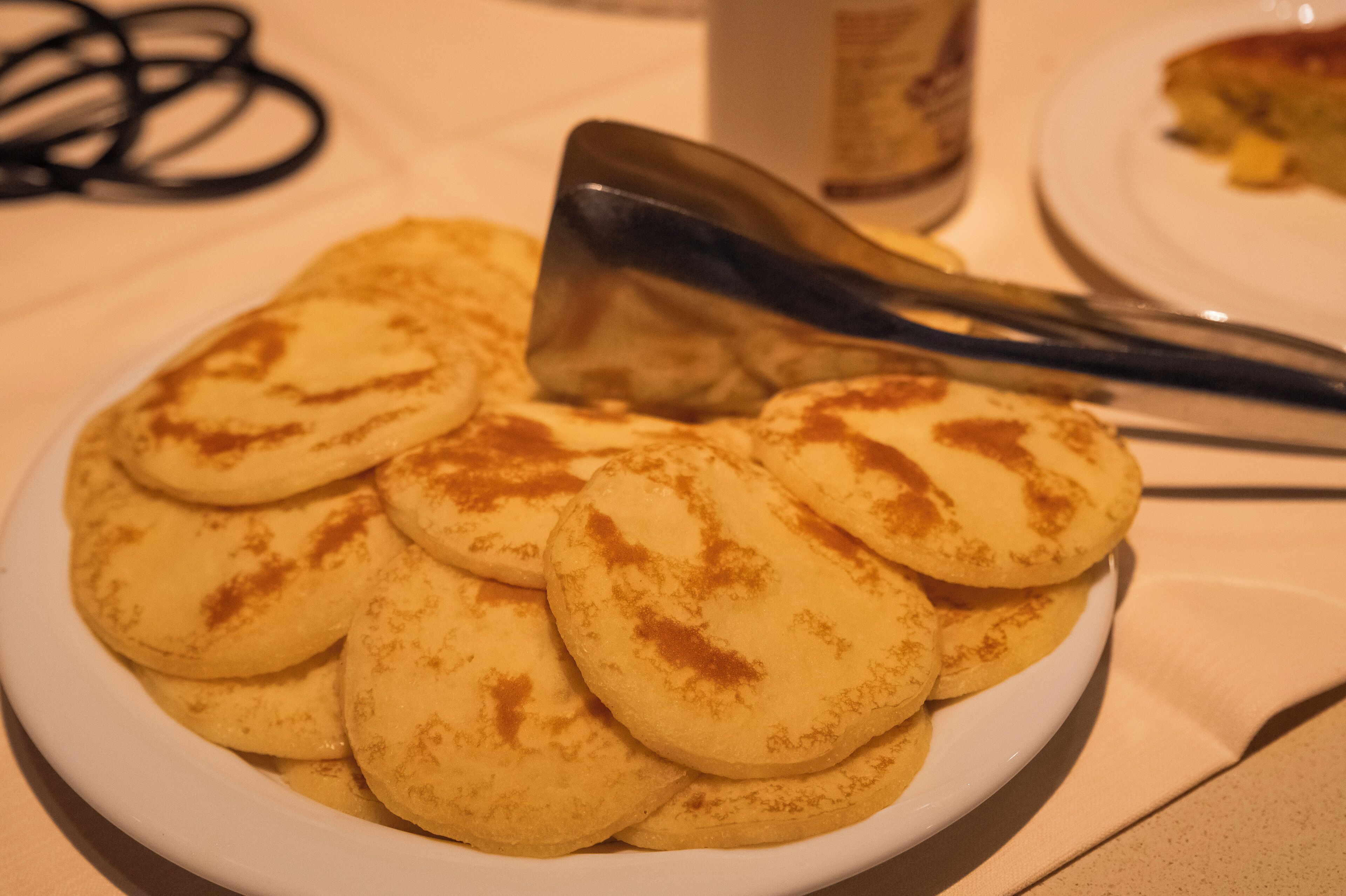 Un plato de tortitas doradas con una espátula encima.