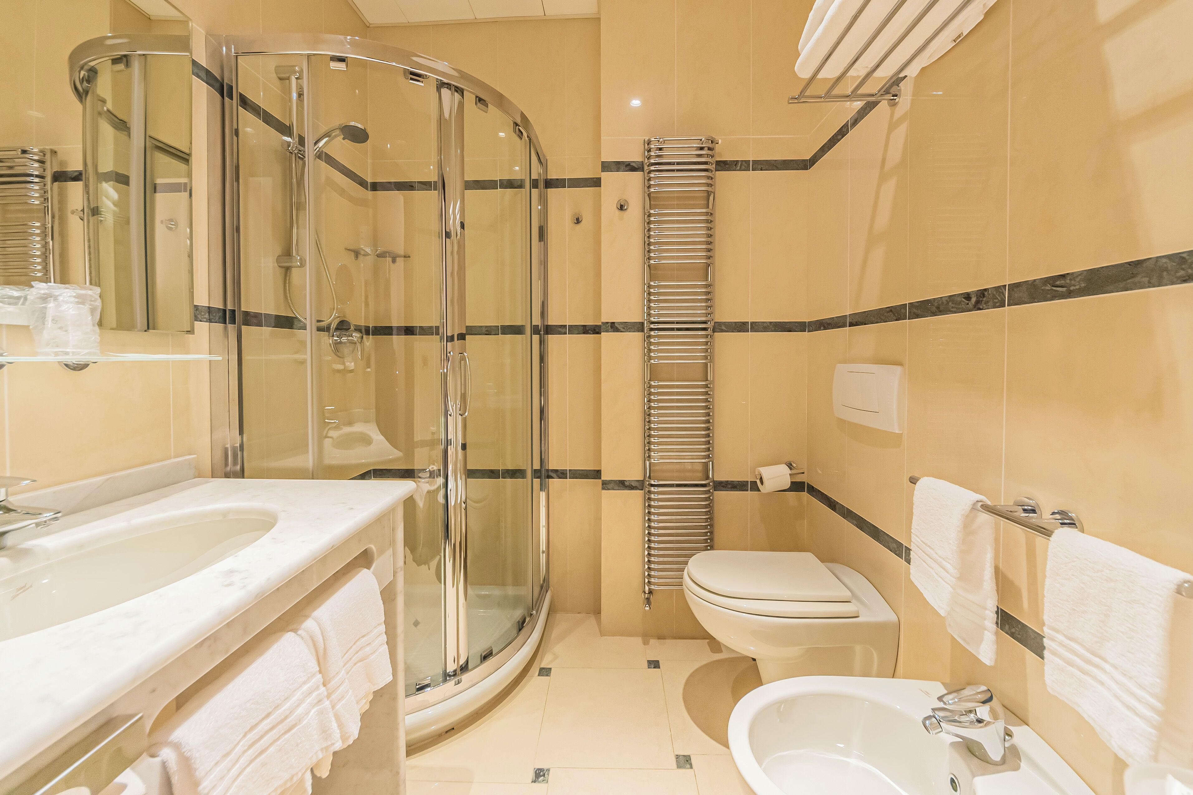 Un bagno moderno con doccia vetrata, lavandino, WC e vasca da bagno.