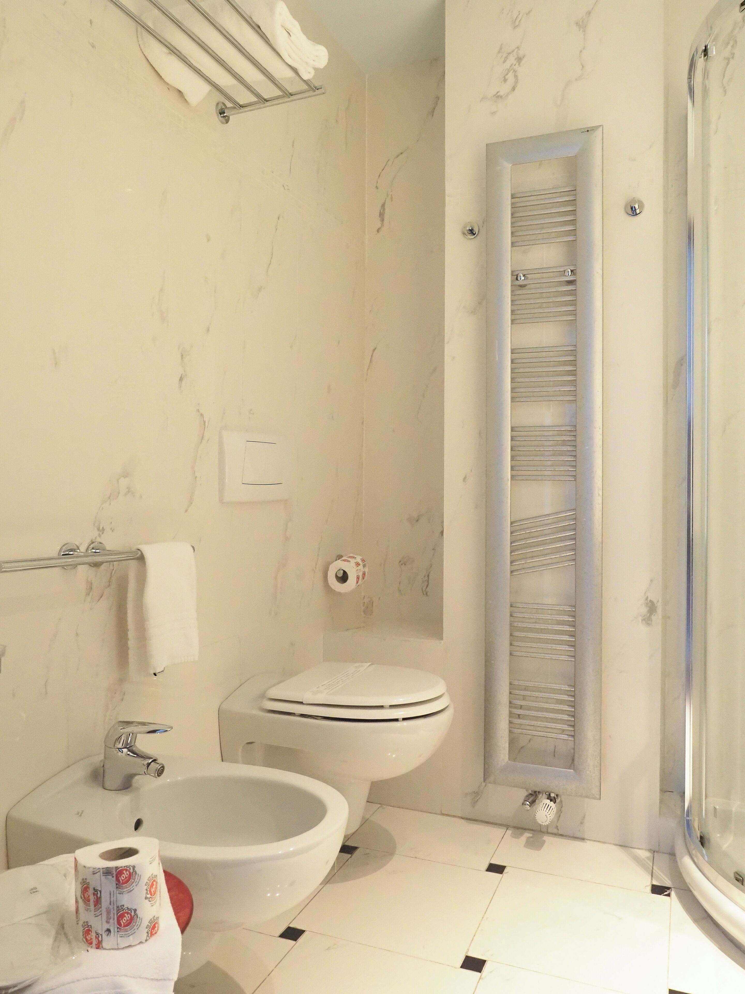 A bathroom with a toilet, bidet, sink, and a shower area.