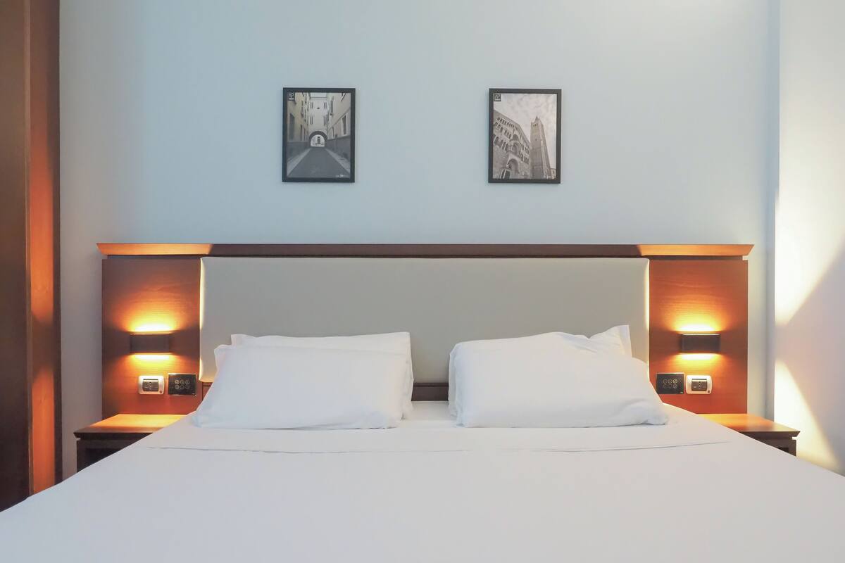 Ein Hotelzimmer mit einem großen Bett, zwei Nachttischen und zwei Wandlampen.
