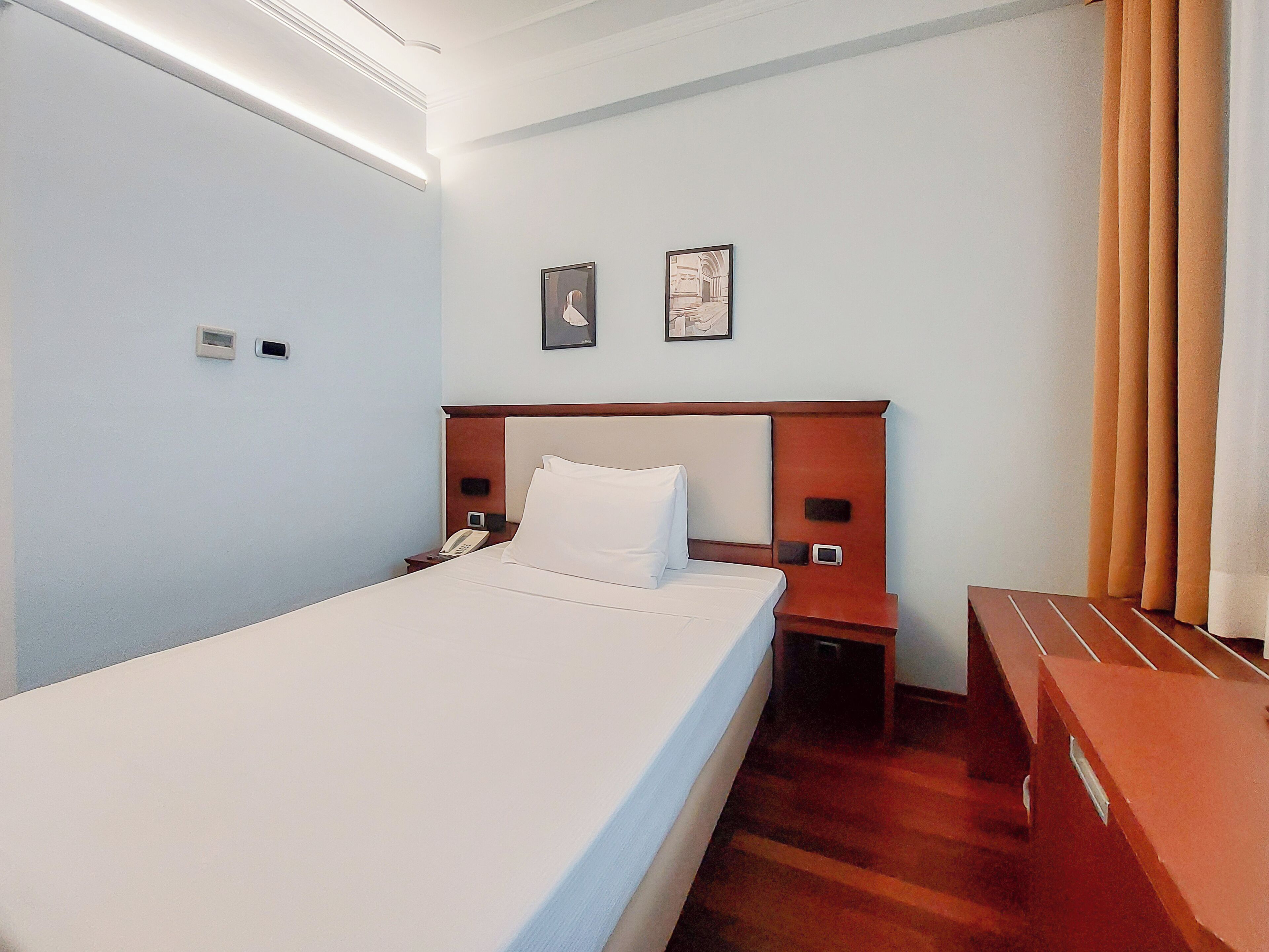 Una habitación de hotel con cama, mesitas de noche y un escritorio.