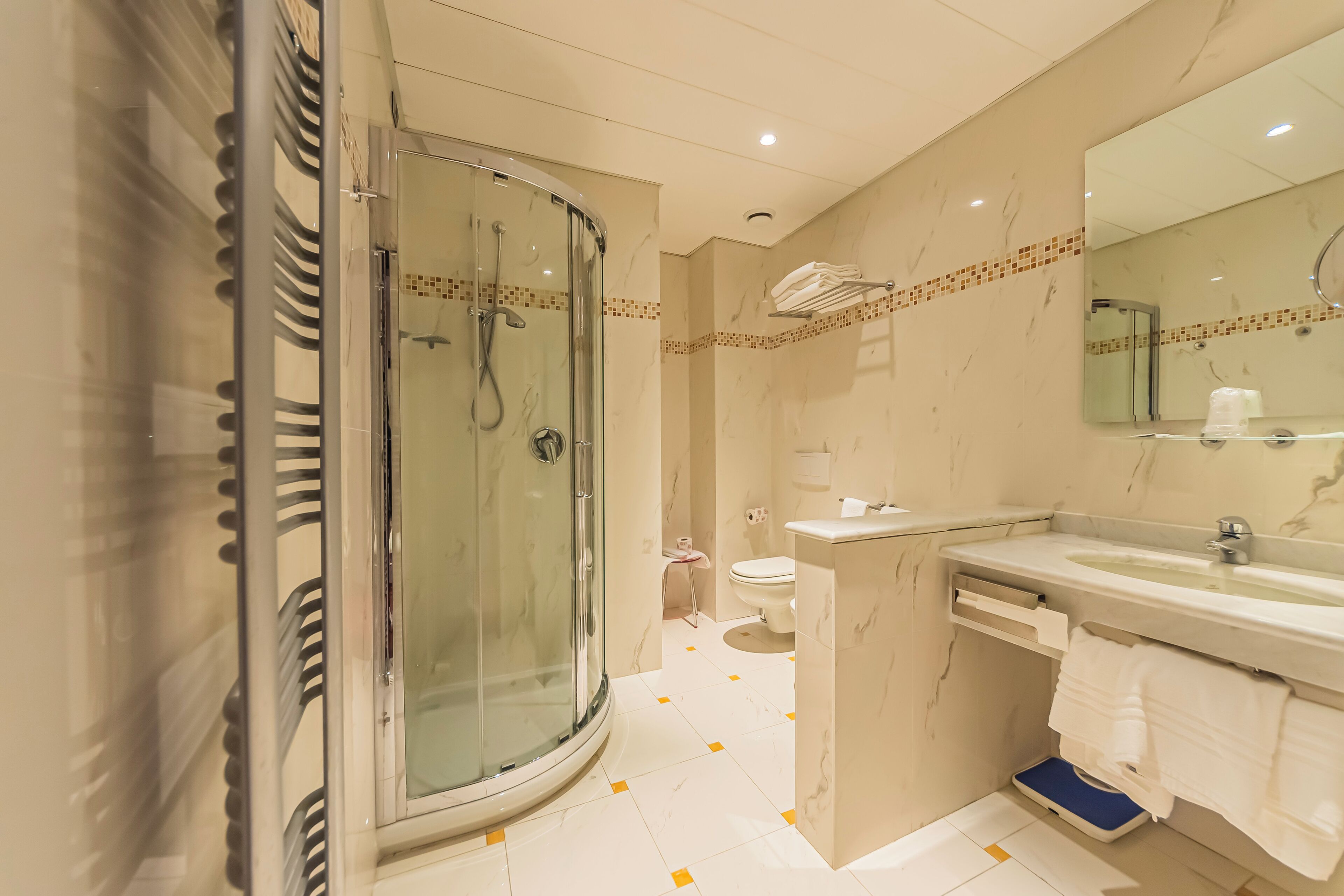 A modern bathroom with a glass-enclosed shower, a sink with a mirror, and a toilet.