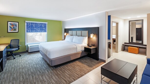 Quarto de hotel com cama, escrivaninha, cadeira e uma pequena mesa.
