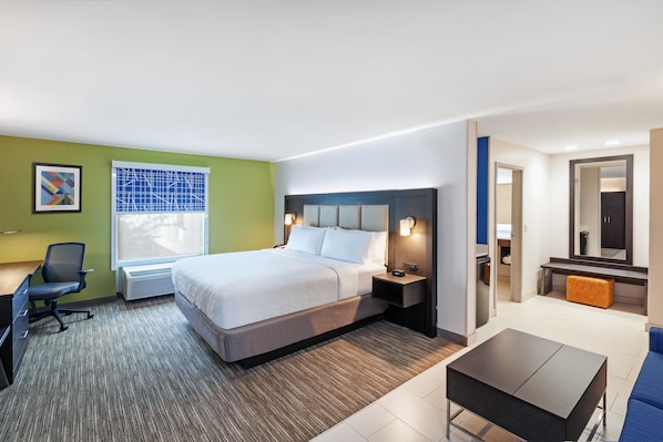 A hotel room with a bed, desk, chair, and a small table.