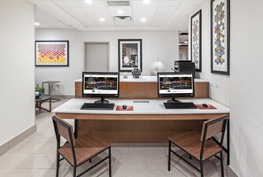 Una reception con due monitor, un vaso decorativo e opere d'arte incorniciate al muro.