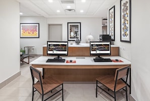 Un mostrador de recepción con dos monitores, un jarrón decorativo y obras de arte enmarcadas en la pared.