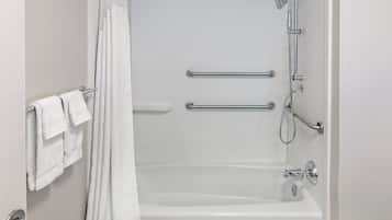 A white bathtub with a shower head, grab bars, and a towel rack.