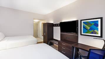 A hotel room with two beds, a desk with a chair, a TV, and a framed abstract painting.
