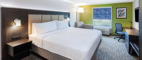 Una habitación de hotel con una cama grande, mesitas de noche, un escritorio con una silla, televisión y ventana con vistas.