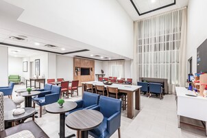Un moderno vestíbulo de hotel con comedor, asientos y un amplio ventanal.