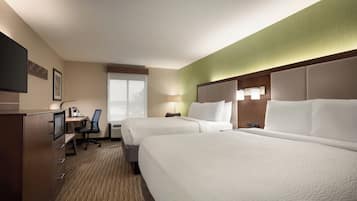 A hotel room with two beds, a desk, a chair, a TV, and a window.