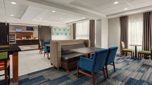 A hotel lobby with a seating area, a counter, and a patterned wall.