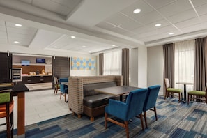 A hotel lobby with a seating area, a counter, and a patterned wall. - Holiday Inn Express Hotel & Suites Atlanta-Cumming by IHG (Cumming)