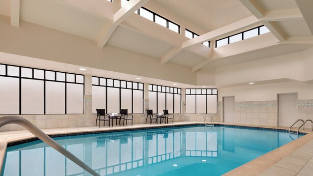 An indoor swimming pool with clear blue water, tiled walls, and a high ceiling with skylights.