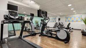 Un gimnasio con cintas de correr, elípticas y bicicletas estáticas.