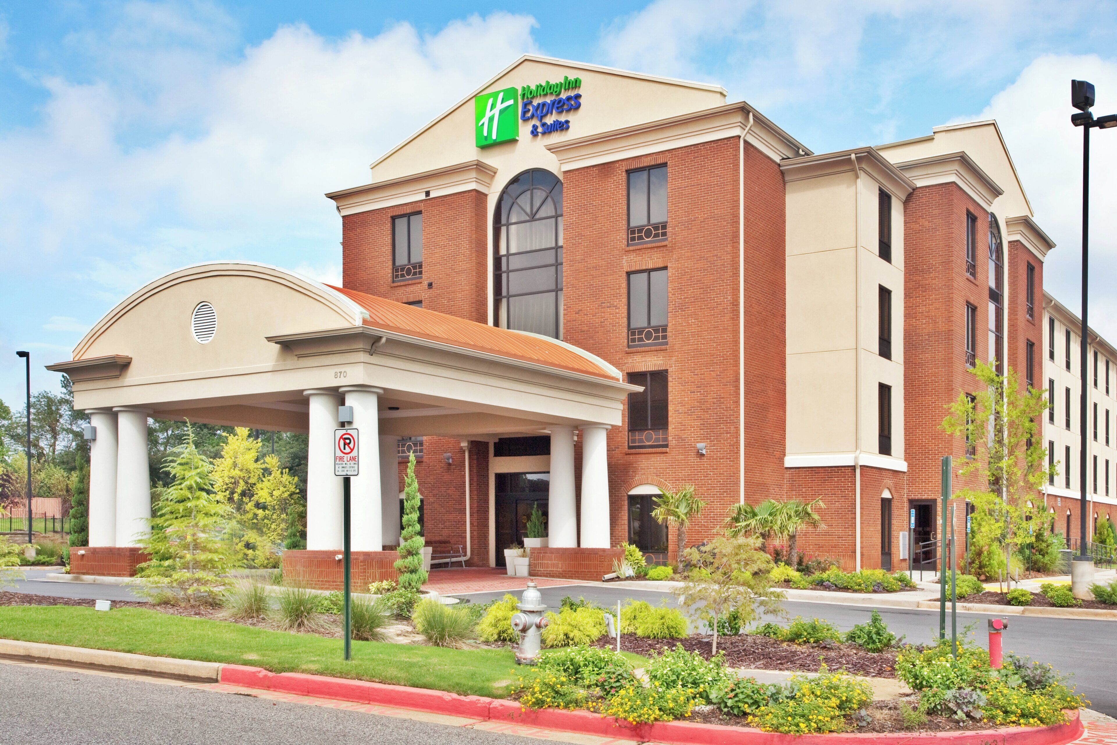 Ett Holiday Inn Express & Suites-hotell med en fasad av tegel, en överbyggd entré och en skylt som visar var utryckningsfordon får köra.
