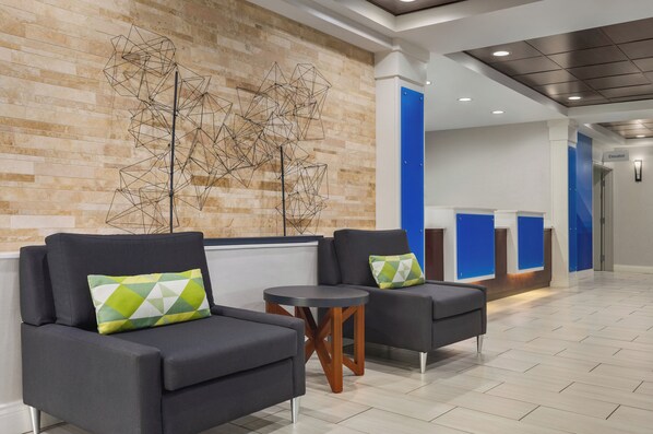 A lobby with two sofas, a small round table, and a geometric wall art piece. - Holiday Inn Express Hotel & Suites Atlanta-Cumming by IHG (Cumming)