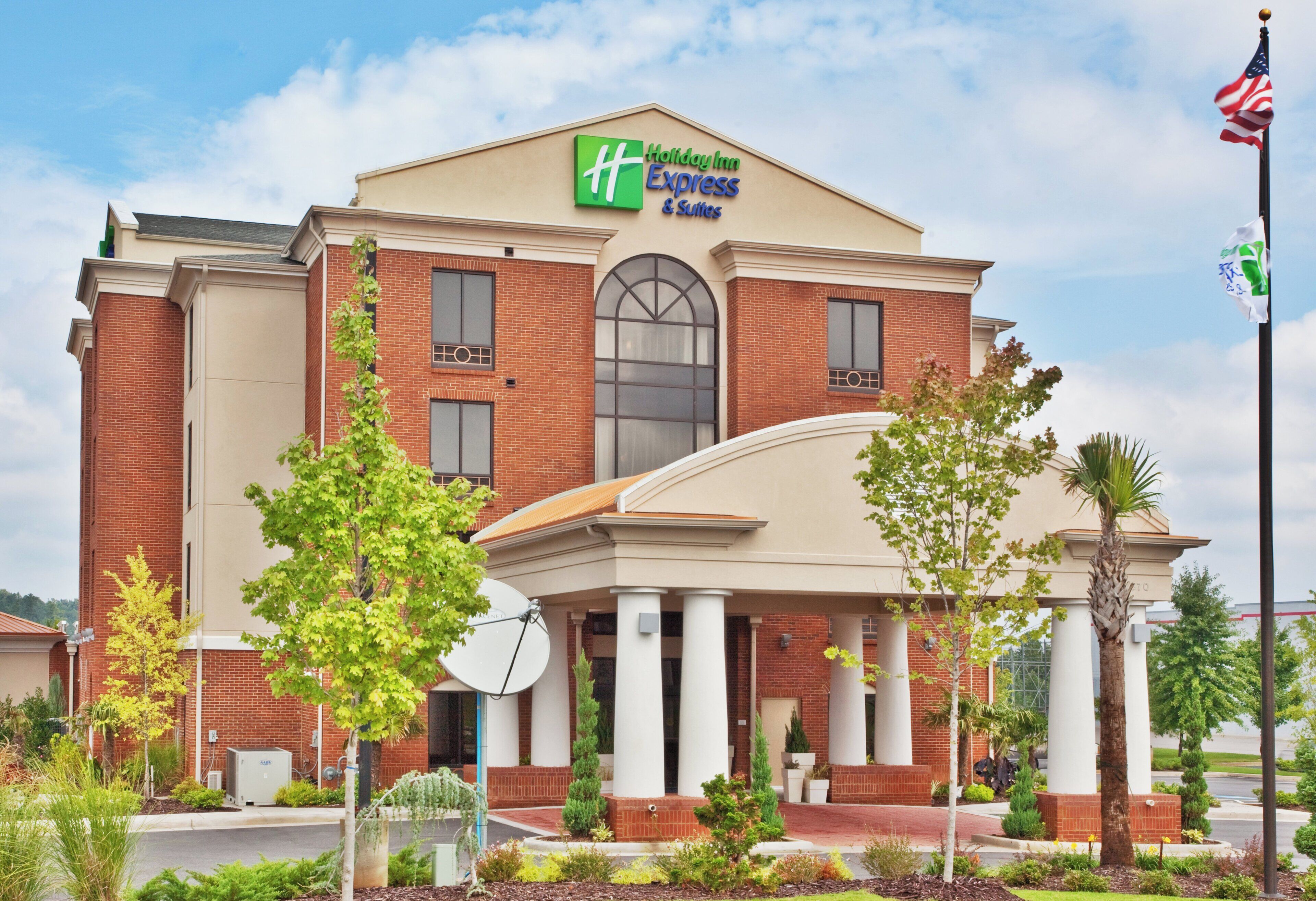 A Holiday Inn Express & Suites hotel with a brick facade, large windows, and a central entrance with columns.