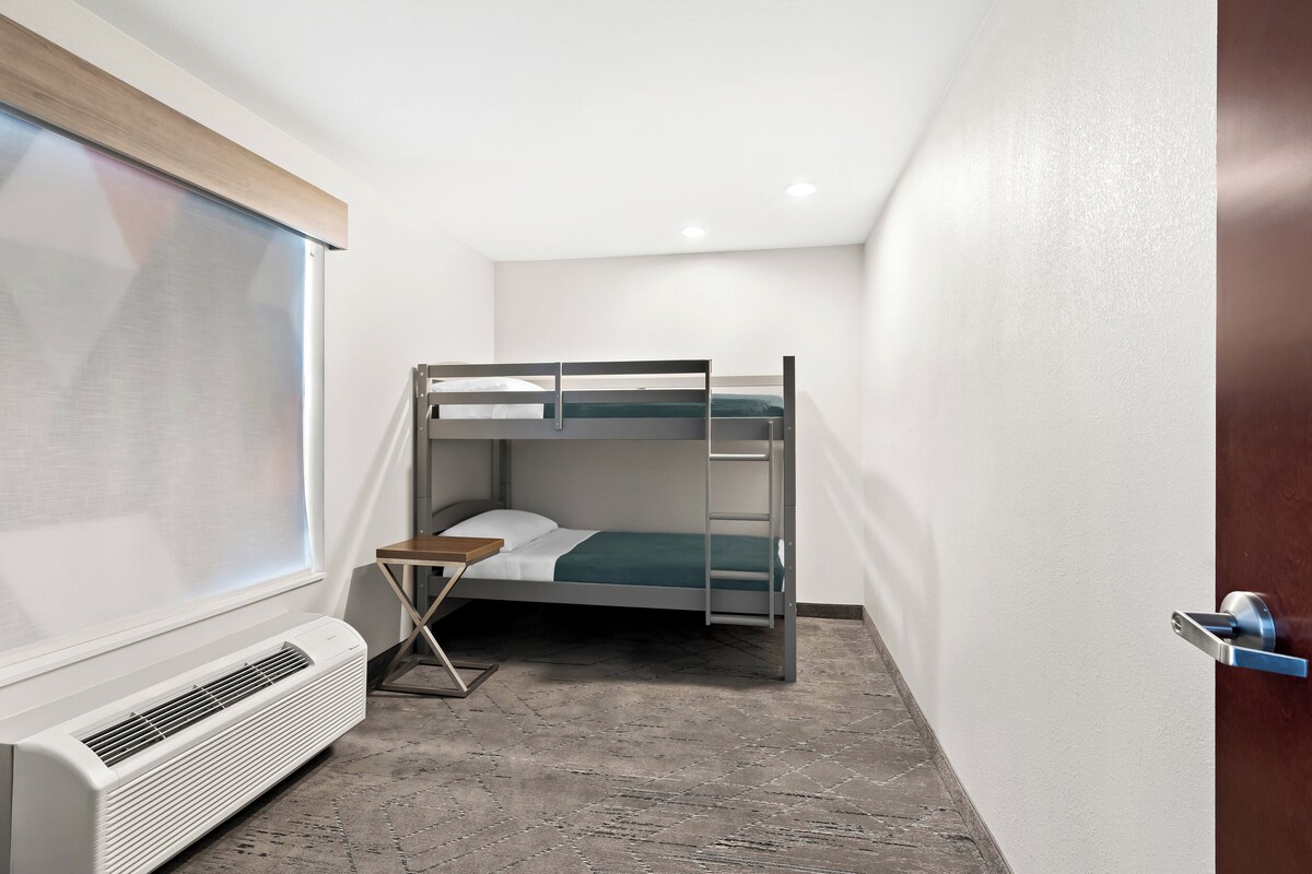 Una habitación pequeña y moderna con literas, un calentador, una mesita y una ventana.