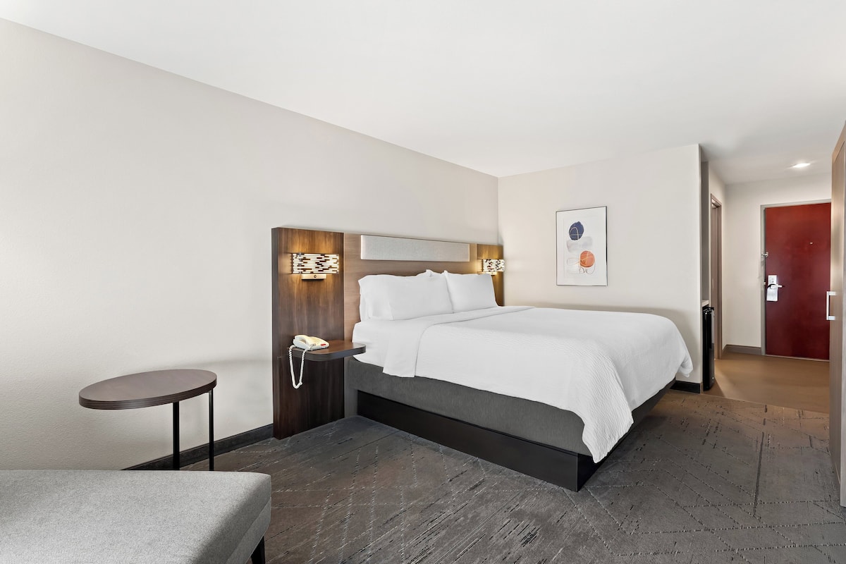 A hotel room with a bed, bedside table, and a small round table.