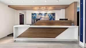 Un comptoir d’accueil au design moderne, agrémenté d’un élément décoratif en bois et d’une enseigne indiquant « Hilton Express & Suites ».