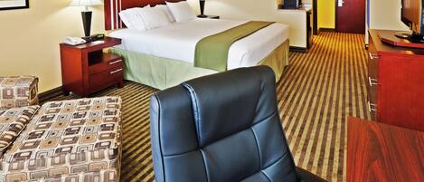 Una habitación de hotel con una cama, mesitas de noche, un escritorio, una silla y un reposapiés estampado.