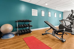 A fitness center with exercise equipment, a wall-mounted dumbbell rack, and exercise balls.