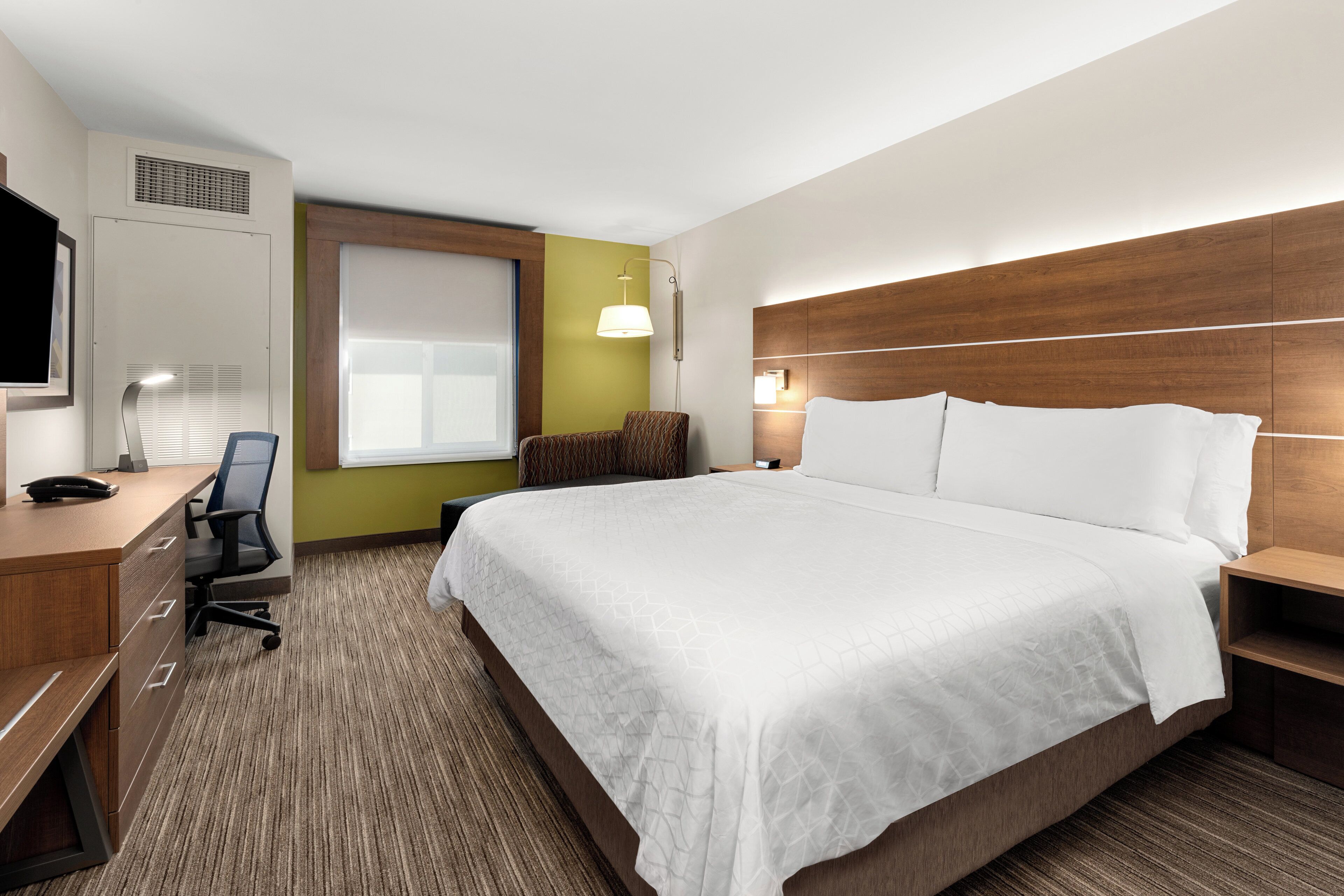 Habitación de hotel con cama, escritorio, silla y televisor.
