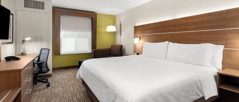 Habitación de hotel con cama, escritorio, silla y televisor.