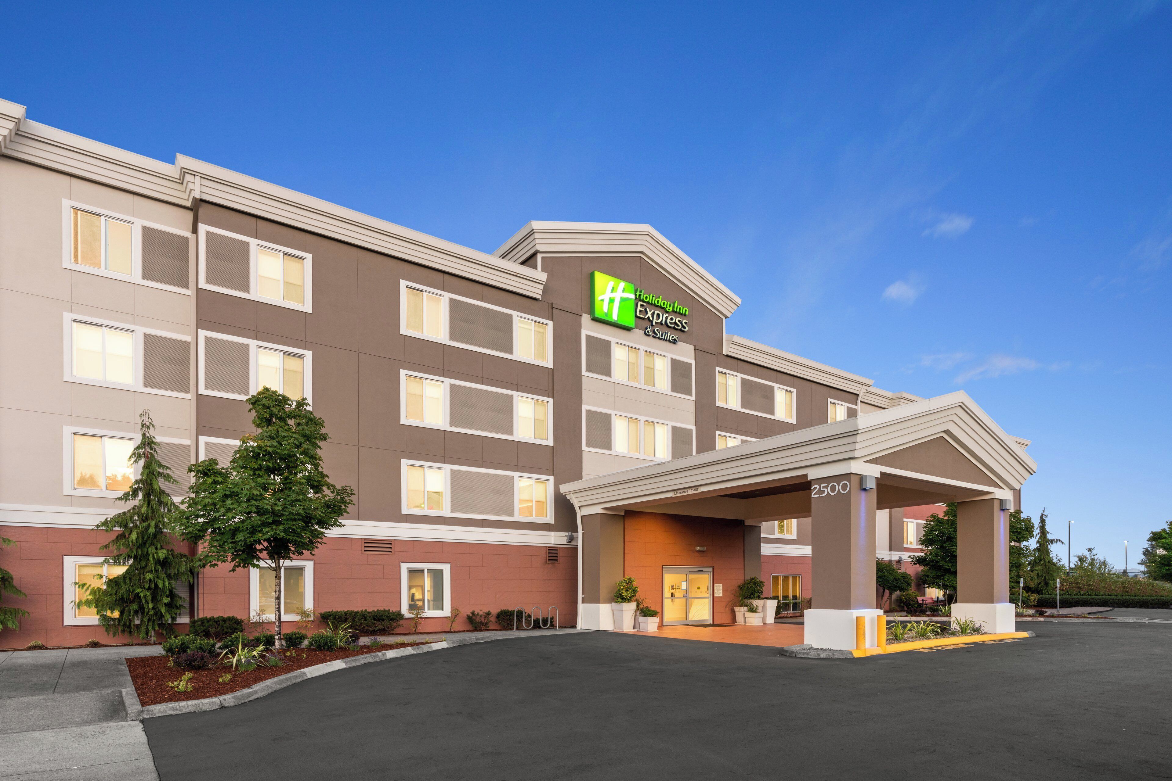 A Holiday Inn Express & Suites building with a covered entrance, multiple windows, and a parking lot.