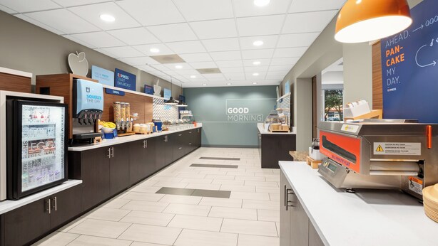A modern breakfast area with a counter, a refrigerator, and a wall with a 'Good Morning' sign. - Holiday Inn Express Suites Sumner by IHG (Sumner)