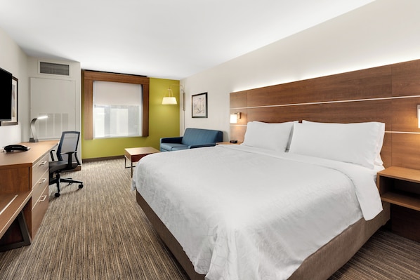 A hotel room with a bed, a desk, a chair, a TV, and a window.