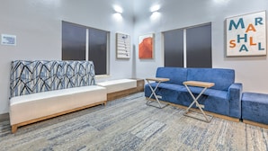 Un espace d’attente moderne avec un canapé à motifs, un canapé bleu et une petite table.