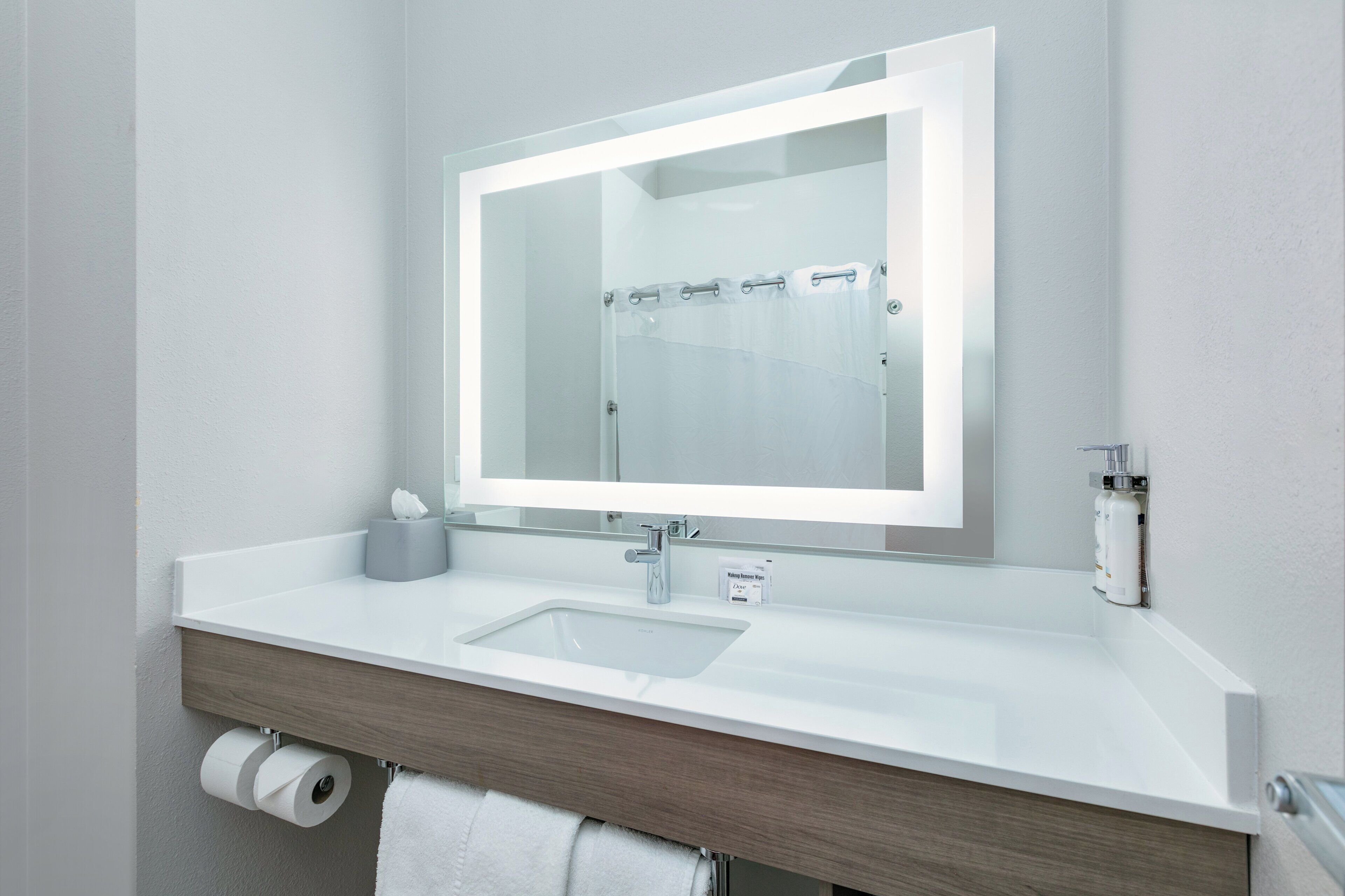 Un baño moderno con un lavamanos blanco, un espejo y una cortina de ducha.