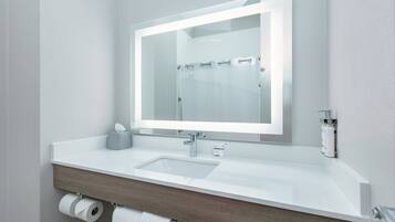 Un baño moderno con un lavamanos blanco, un espejo y una cortina de ducha.
