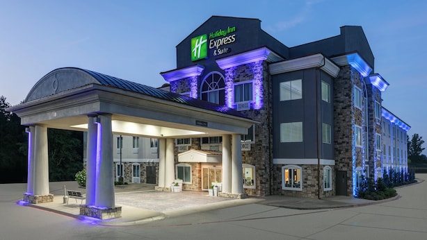 Un bâtiment de l’hôtel Holiday Inn Express & Suites doté d’une entrée abritée, d’une façade en pierre et d’une enseigne lumineuse.