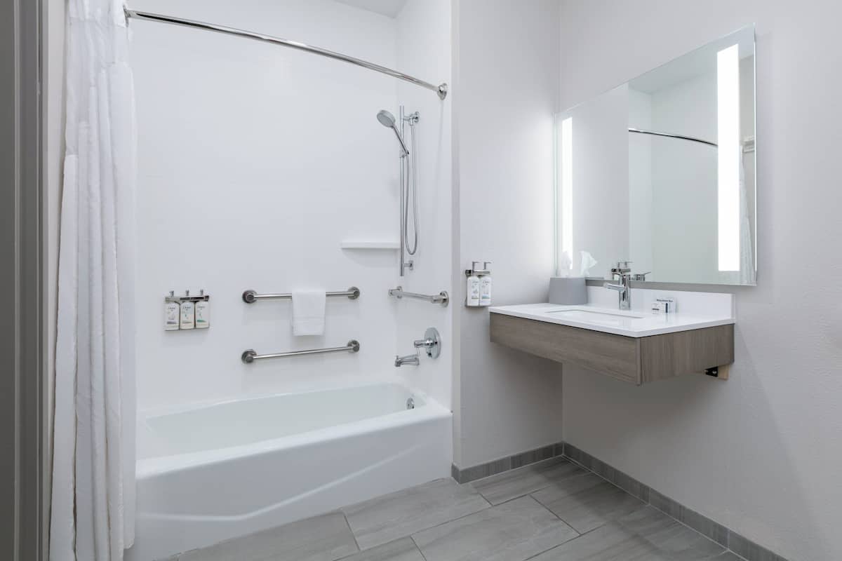 A modern bathroom with a bathtub, shower, and vanity.