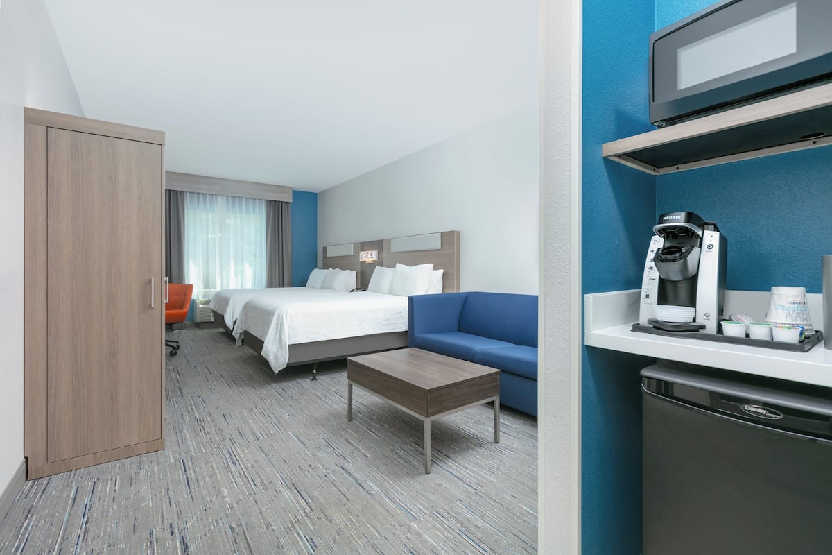 A hotel room with a bed, a sofa, a coffee machine, and a microwave.