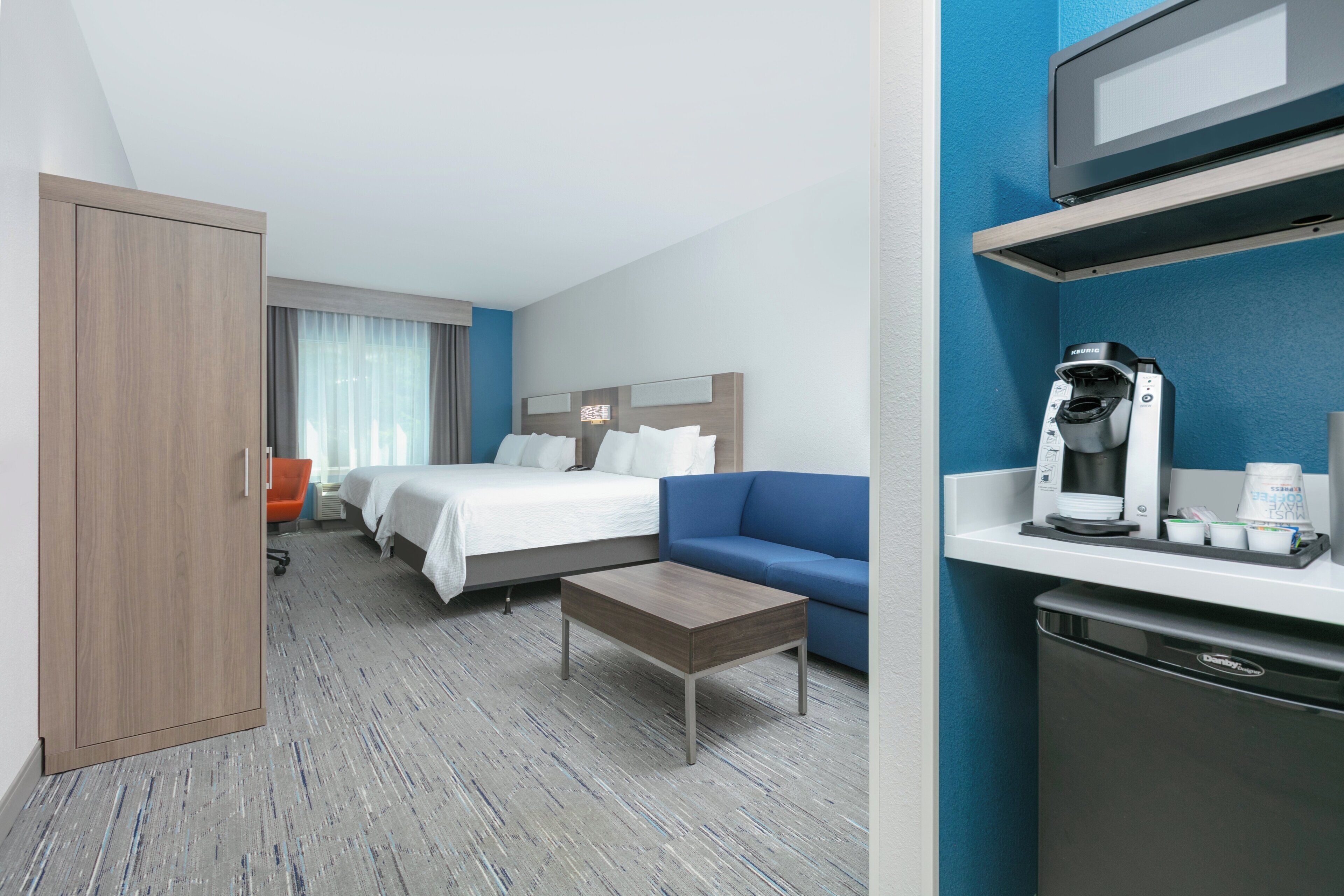Ein Hotelzimmer mit einem Bett, einer Couch, einer Kaffeemaschine und einer Mikrowelle.