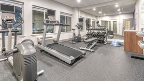 Une salle de sport équipée de tapis de course, de vélos elliptiques et de poids libres.
