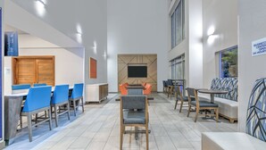 A spacious indoor area with multiple seating arrangements, including tables and chairs, and a flat-screen TV mounted on the wall. - Holiday Inn Express & Suites Marshall by IHG (Marshall)