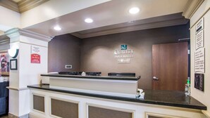 Un comptoir d’accueil d’hôtel avec une enseigne indiquant « Quality Inn & Suites ».