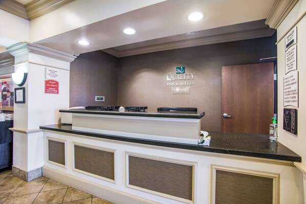 Mostrador de recepción de hotel con un letrero que dice 'Quality Inn & Suites'.